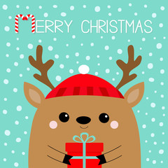 Merry Christmas. Raindeer deer head face holding gift box. Red hat, nose, horns. Happy New Year. Cute cartoon kawaii baby character. Funny animal. Flat design. Hello winter. Blue snow background.