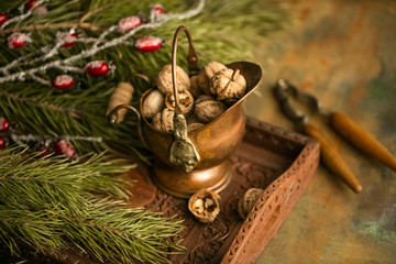 Fototapeta na wymiar walnut in a copper bowl on a wooden table with branches of spruce. copy space