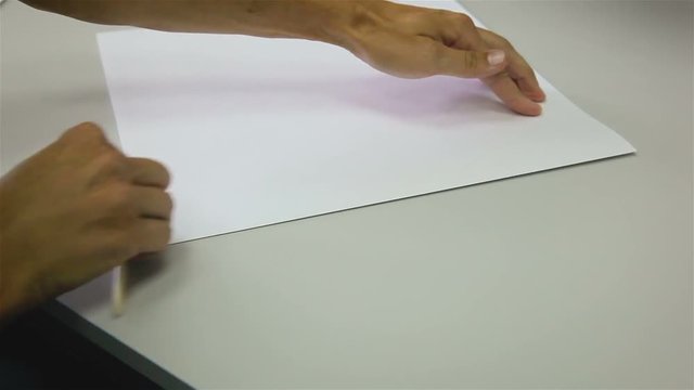 Close-up of the male hand preparing section for the production of books by hand in the workshop