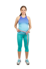 Sporty pregnant woman with a measure tape in the hands, isolated