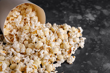 Snack for watching movies. Popcorn fallen out of a white bucket on a textural background.