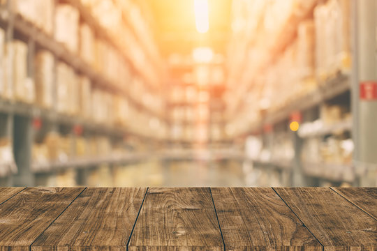 Warehouse inventory in blur for background with empty wooden foreground space.