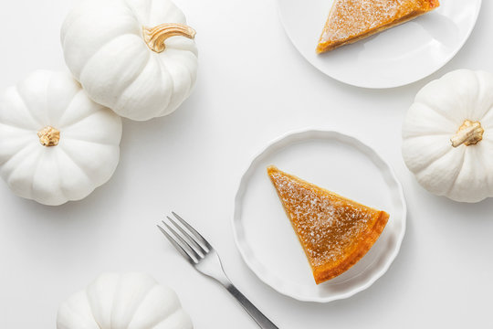 Pumpkin pie on a white plate with pumpkins on a white background, homemade autumn food for thanksgiving concept