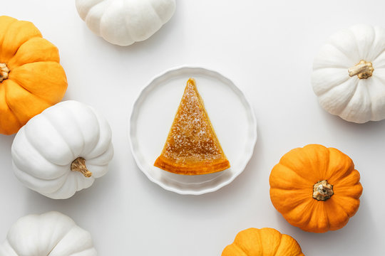 Pumpkin Pie On A White Plate With Pumpkins On A White Background, Homemade Autumn Food For Thanksgiving Concept