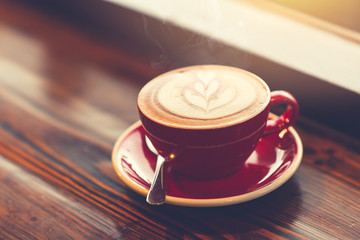 good morning coffee at windows on wooden table with latte art vintage color tone.