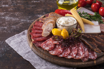 Appetizer with different sausages and pickled vegetables on wooden board. Copy space. Rustic style