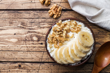 Healthy breakfast. Cottage cheese with banana and walnuts on wooden background.