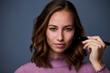 Fototapeta premium Beautiful brunette applying make up, portrait