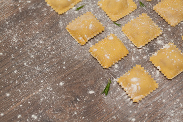 Tasty raw ravioli with flour on wooden background. Process of making italian ravioli. Selective focus