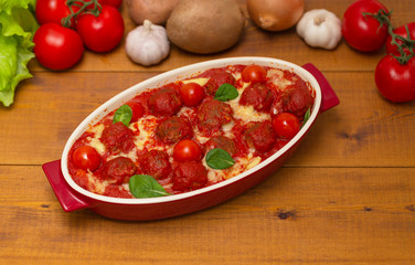 Meatballs in tomato sauce in a baking dish on a wooden table. Selective focus
