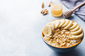 Healthy breakfast. Cottage cheese with banana and walnuts on grey background.