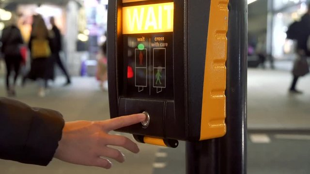 Pedestrian pushes button and waits for the green sign at a crossing