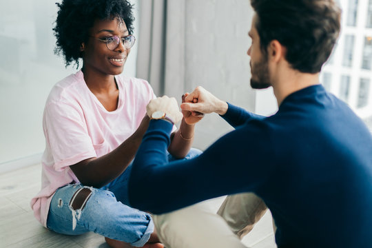 People, Lifestyle And Relaxation Concept, Two Young Multi-ethnic Lovers Sit Opposite Each Other With Joined Hands, Feeling Spiritual Unity And Love