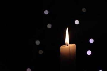 Burning candle with bokeh lights