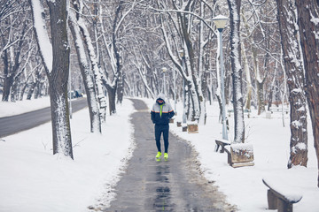 Fototapeta na wymiar Man jogging in snowy park and cold weather.