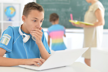 Portrait of cute little boy using laptop at classroom