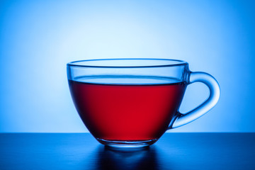  Glass transparent cup with a drink on a bright multi-colored background.