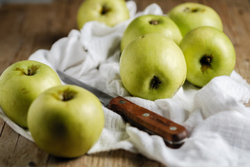 green ripe apples on old wooden table with a knife