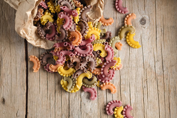 Raw colored pasta scattered on the wooden old table