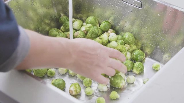 washing raw Brussels sprouts in kitchen sink