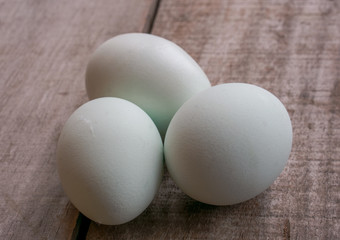 Three white eggs on wooden background