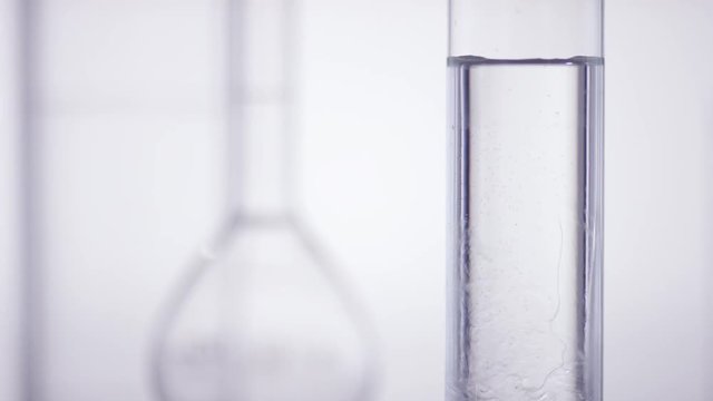 test tube get filled with viscous liqud inf front of white background