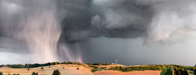 Storm, clouds, rain and rainbow on the hill