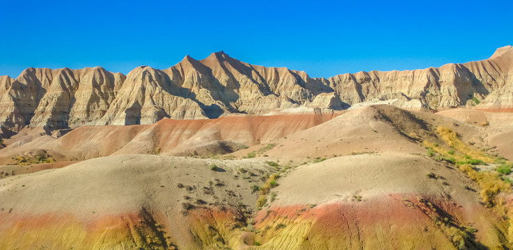 Panorama of colorful eroded pinnacles of Badlands National Park in South Dakota, United States. American travel destination. Summer blue sky with copy space.