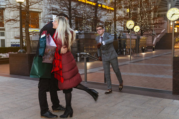 Fototapeta premium The happy young couple hugging after the good shopping outdoor and rejoicing