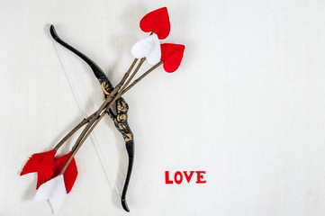 Handmade cupid's twig arrows, bow and letters LOVE on a white wooden background. Copy space, top...