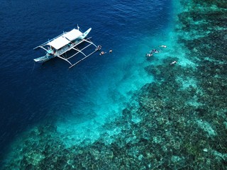 An aerial shot of an island hopping boat around Palawan Islands in the Philippines