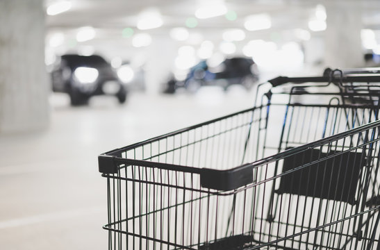 empty shopping cart and blurred car at parking lot, winter color tone