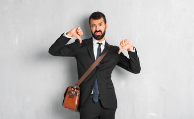 Businessman with beard showing thumb down with both hands