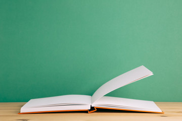 Open note book on wooden desk with green background