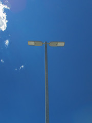 Light pole against a blue sky with some white cloud low angle shot    