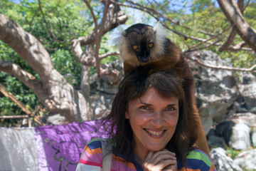 Lemur sits on the head of a woman on the  Nosy Komba island