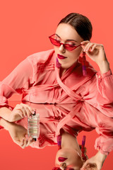 glamouröse frau in bluse und roter sonnenbrille posiert mit parfümflasche und spiegelreflexion isoliert auf lebender koralle © LIGHTFIELD STUDIOS