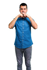 Handsome man with blue shirt showing a sign of closing mouth and silence gesture