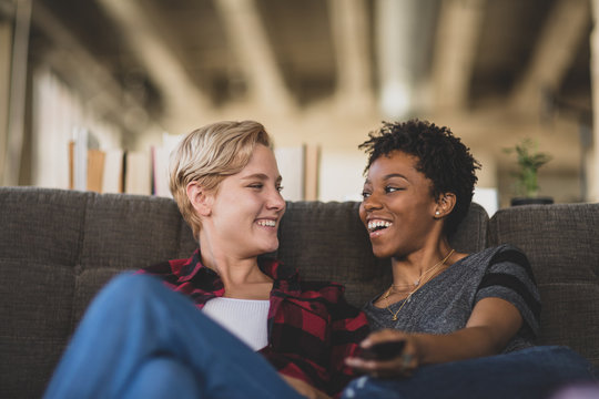 Female couple relaxing on sofa watching home entertainment