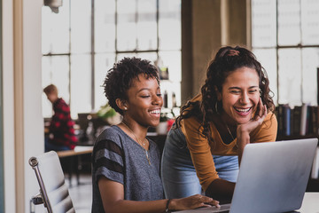 Smiling friends using laptop at home
