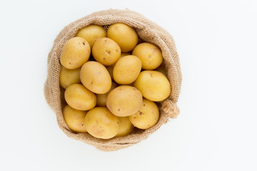 Sack of fresh raw potatoes on wooden background, top view