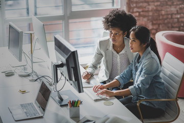 Coworkers looking at a desktop computer together