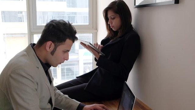 Teamwork between a team working on their computers and discussing sharing and hectically at work with diligence 