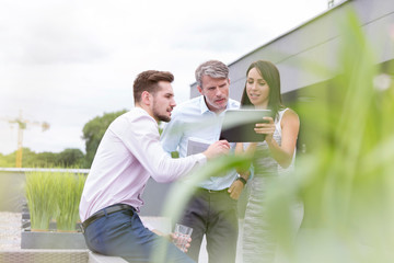 Businesswoman showing digital tablet to colleagues at office terrace