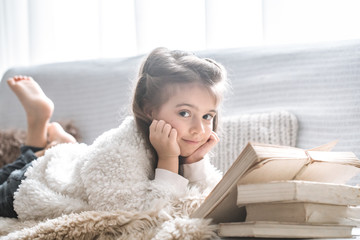 little girl reading a book on a comfortable sofa, beautiful emotions