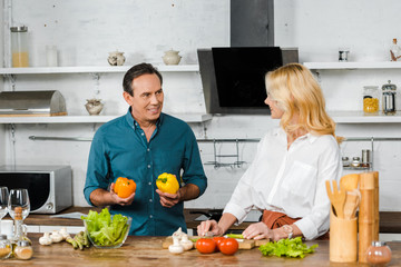 mature couple cooking salad together in kitchen