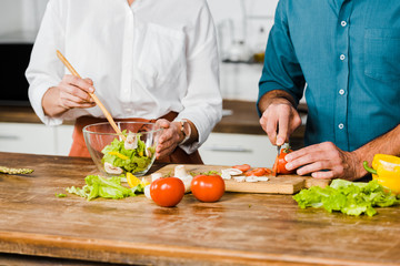 cropped image of mature wife and husband cooking healthy salad together in kitchen