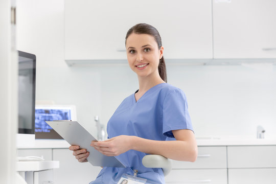Portrait of smiling nurse with clipboard at dental clinic