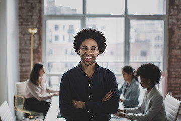 Portrait of smiling businessman with afro hair standing in office