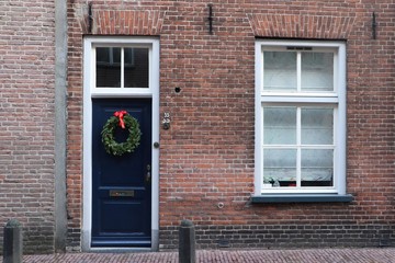 Fototapeta na wymiar Brick wall with window and door with christmas wreath